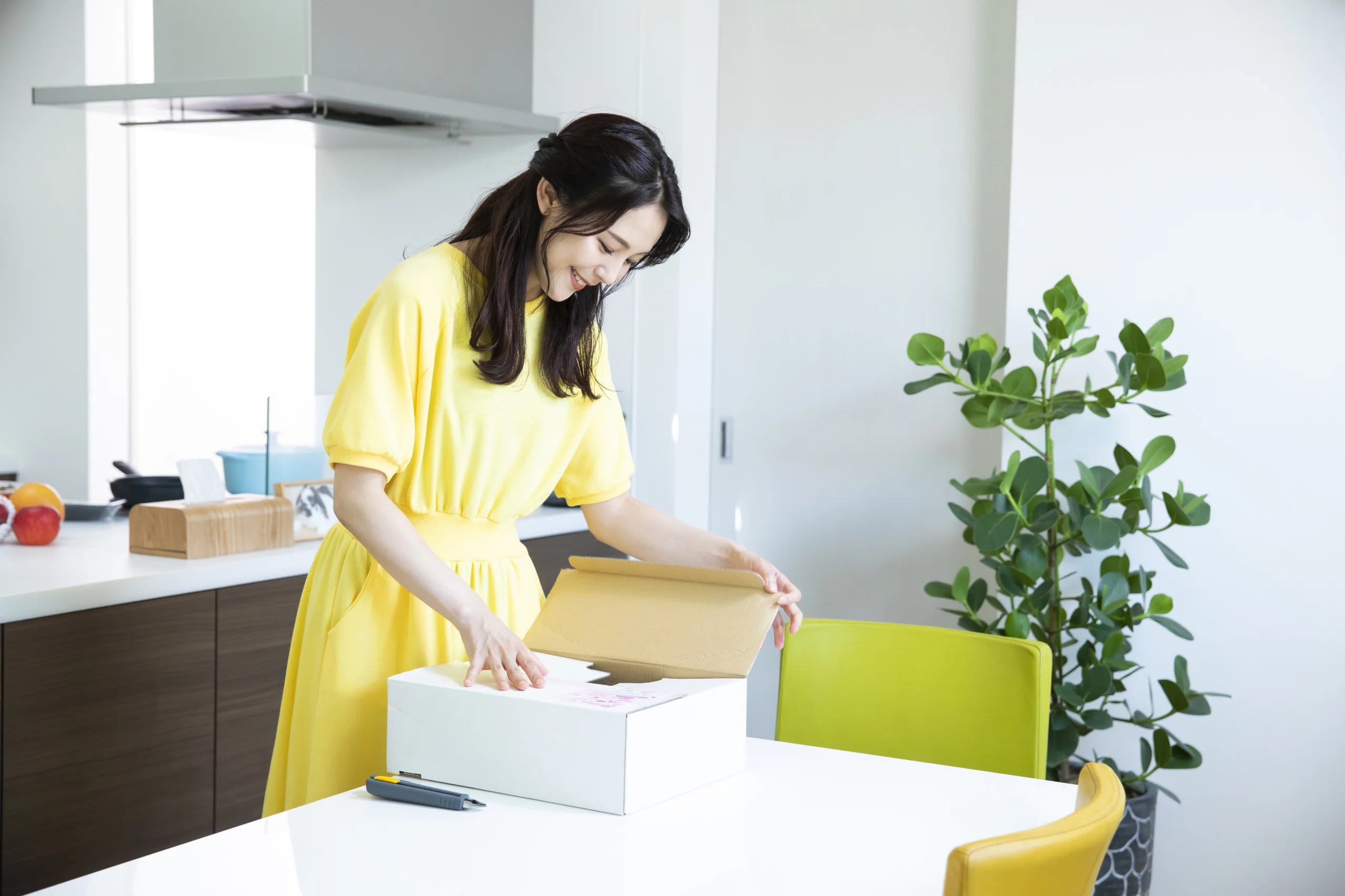 家に届いた梱包された商品を女性が開けています